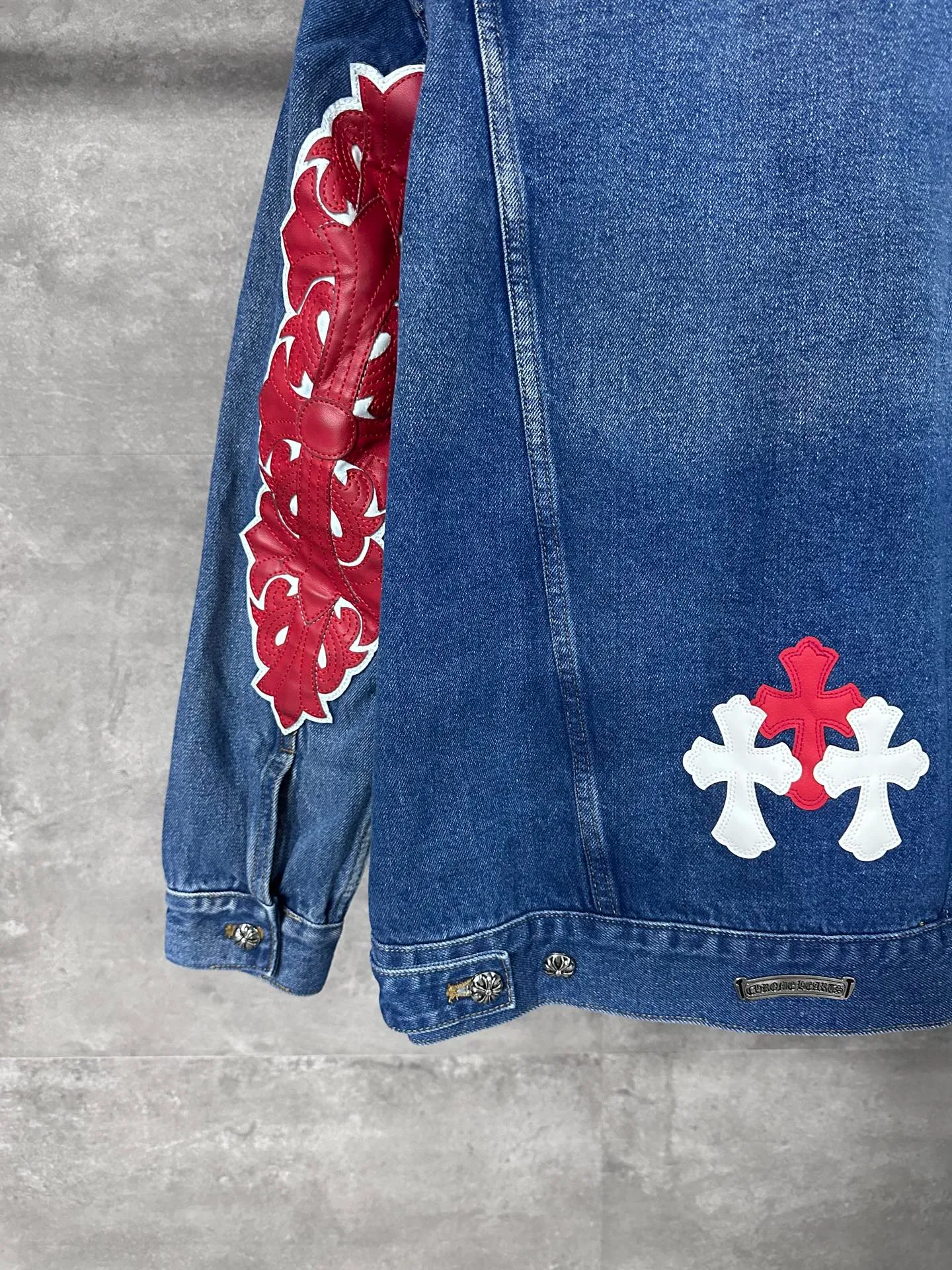 P720 CHrome Hearte cross patchwork leather denim jacket size: S M L Design details: the visual fantasy of Gothic symbols, the multi-dimensional expression of the cross totem: the red and white contrasting cross patches are staggered on the chest and back, making the brand more recognizable; the hollow cross pattern leather splicing on the sleeves combines the mystery of religious symbols with the punk-style deconstructed design. Every detail tells the dark aesthetics of Crowe's heart. Retro distressing with denim texture: Selected denim fabrics are treated with distressing techniques to show natural fading and texture, which not only retains the retro accent of denim items, but also adds a casual sense to the overall look. The ingenuity of hardware and tailoring: The metal buttons and hardware all have Croxin's iconic pattern, which shines exquisitely under the refraction of light; the neat tailoring of the classic denim jacket is suitable for a variety of wearing scenarios, and can create a strong personal style whether it is layered or worn alone. Croxin's denim jacket is not only a piece of clothing, but also a style badge that highlights unique aesthetics and rebellious attitude. For those who pursue individuality, they can leave their own hardcore mark in the fashion field.
